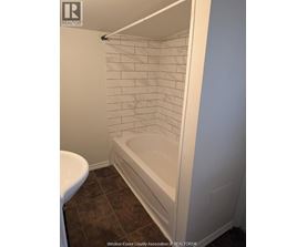 A white tiled shower in a bathroom.