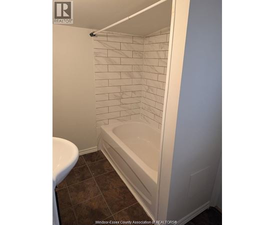 A white tiled shower in a bathroom.