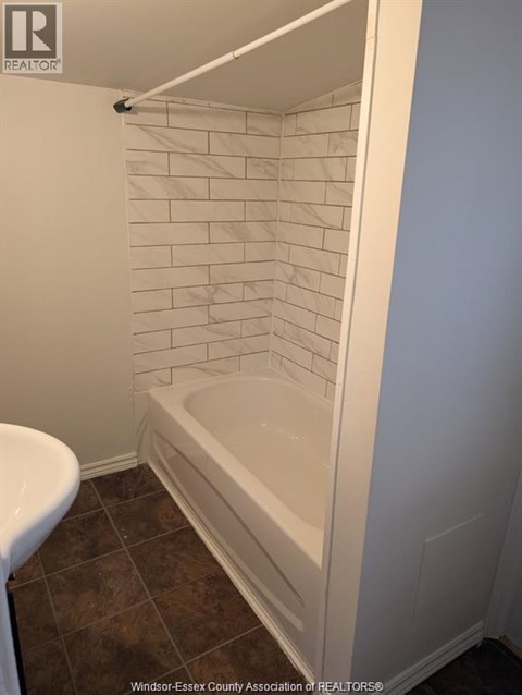 A white tiled shower in a bathroom.