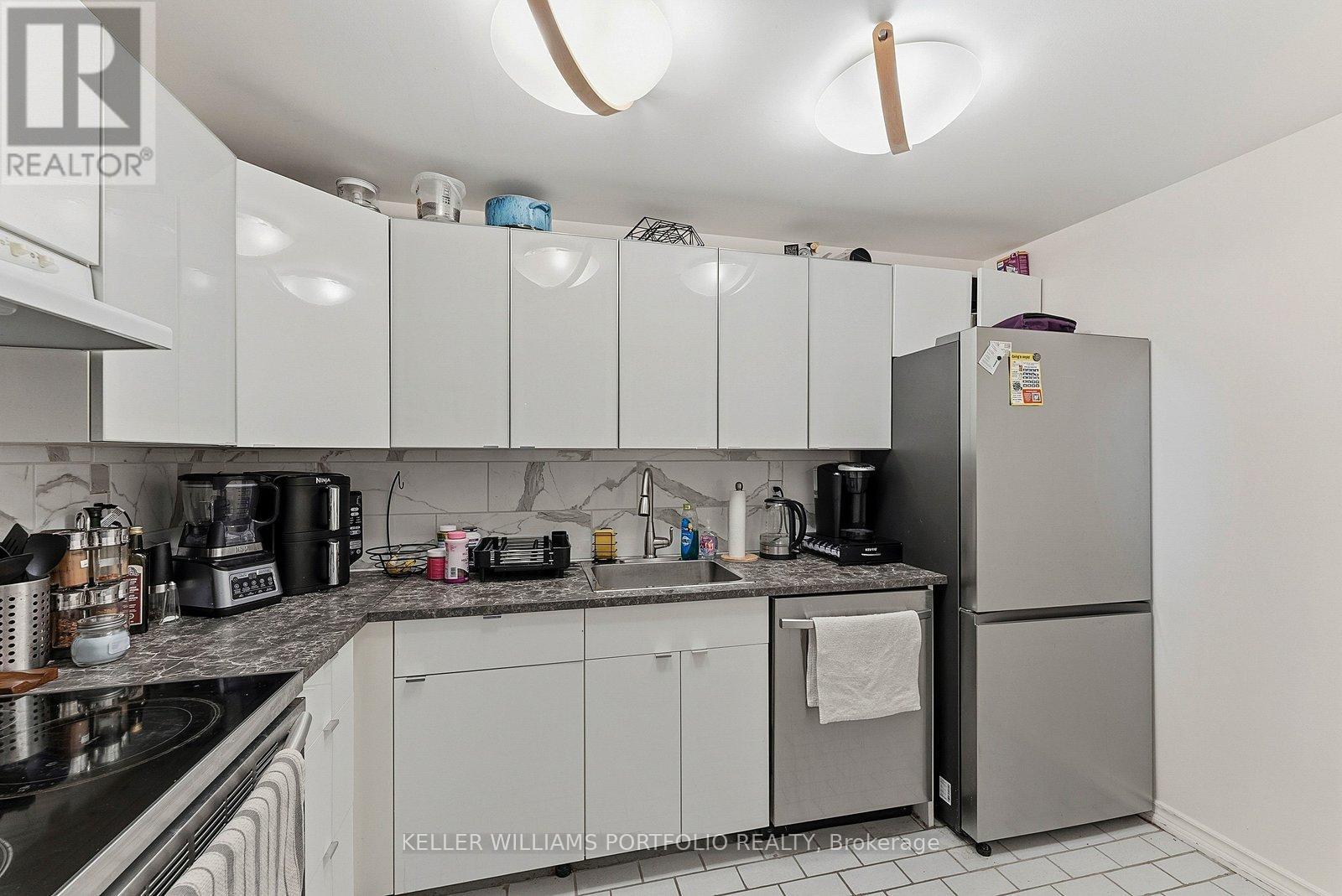 A kitchen with white cabinets and a refrigerator.