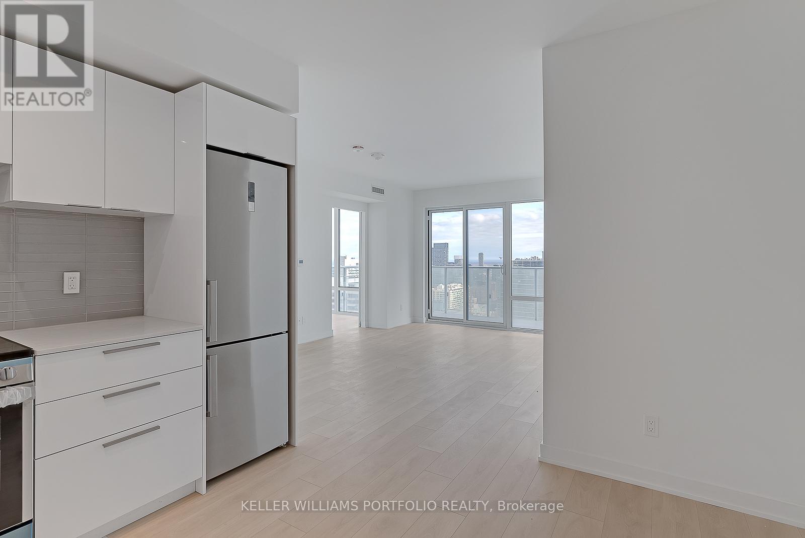 A spacious kitchen with white cabinets and a refrigerator.