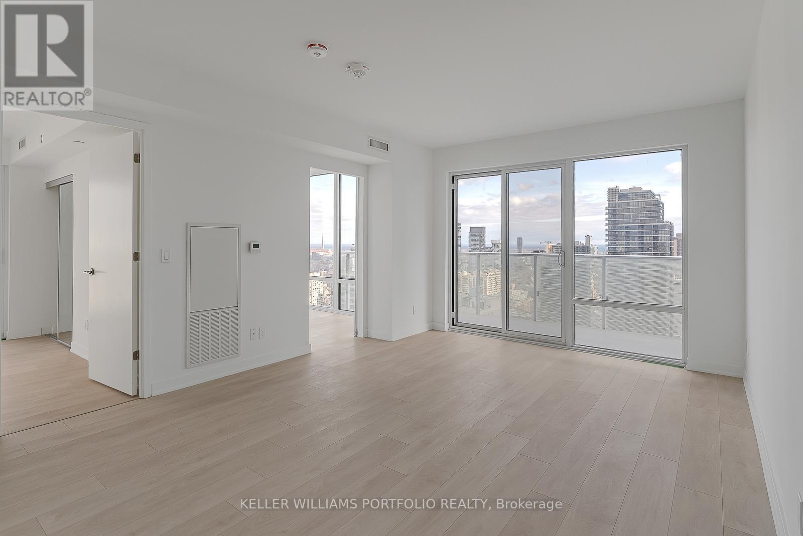 A spacious, empty room with a view of the cityscape outside the large windows.