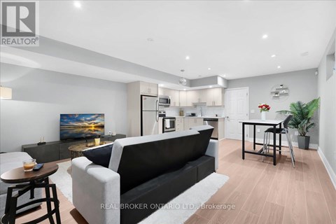 A modern living room with a black couch and a painting on the wall.
