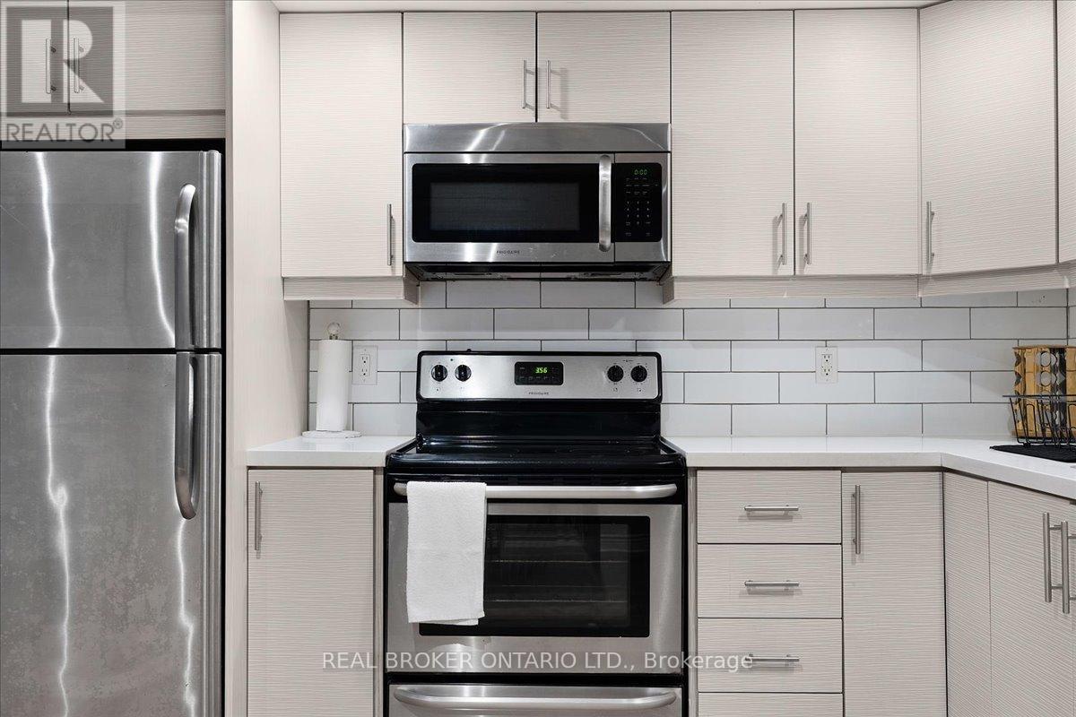 A modern kitchen with a stainless steel refrigerator, a microwave above the stove, and white cabinets.