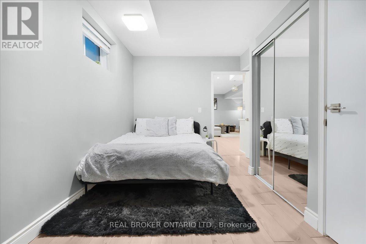 A bedroom with a bed, a chair, and a mirror.