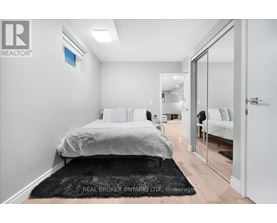 A bedroom with a bed, a chair, and a mirror.