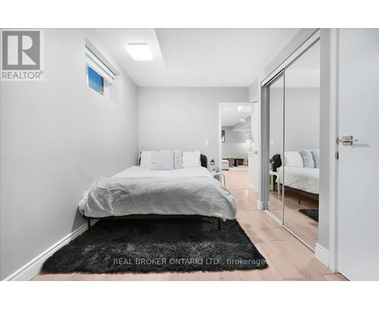 A bedroom with a bed, a chair, and a mirror.