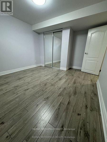 A room with wooden flooring and white walls, with a door on the right and a sliding door on the left.