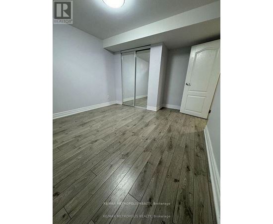 A room with wooden flooring and white walls, with a door on the right and a sliding door on the left.