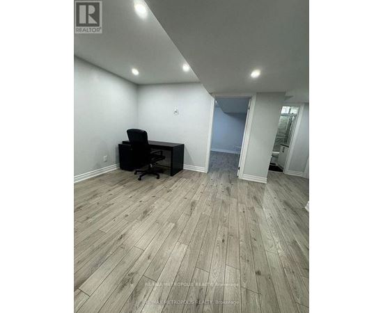 A room with a wooden floor and a black office chair.