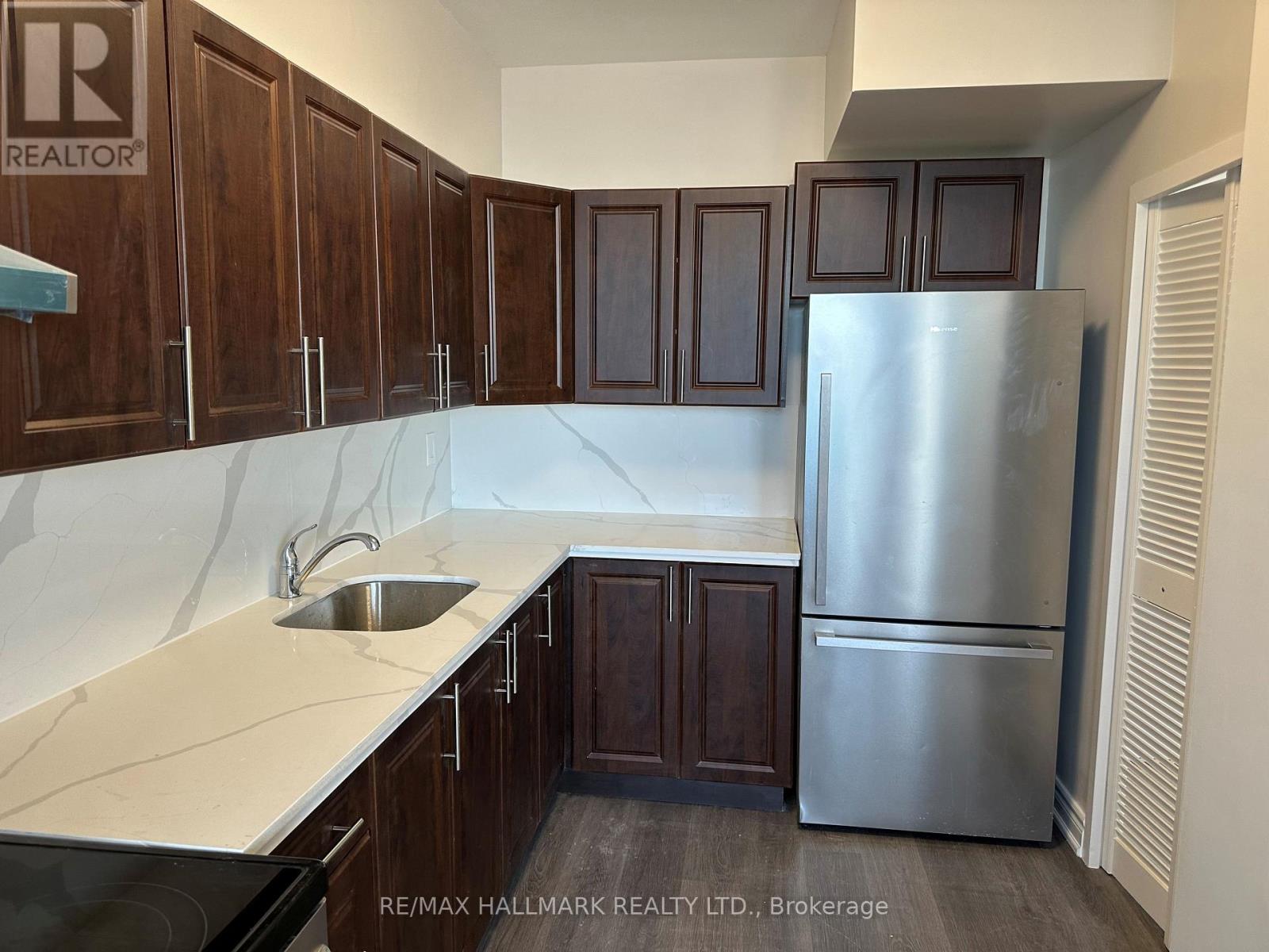 A kitchen with wooden cabinets and a stainless steel refrigerator.