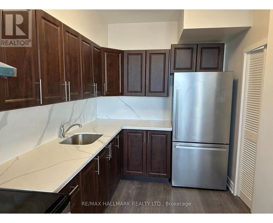 A kitchen with wooden cabinets and a stainless steel refrigerator.