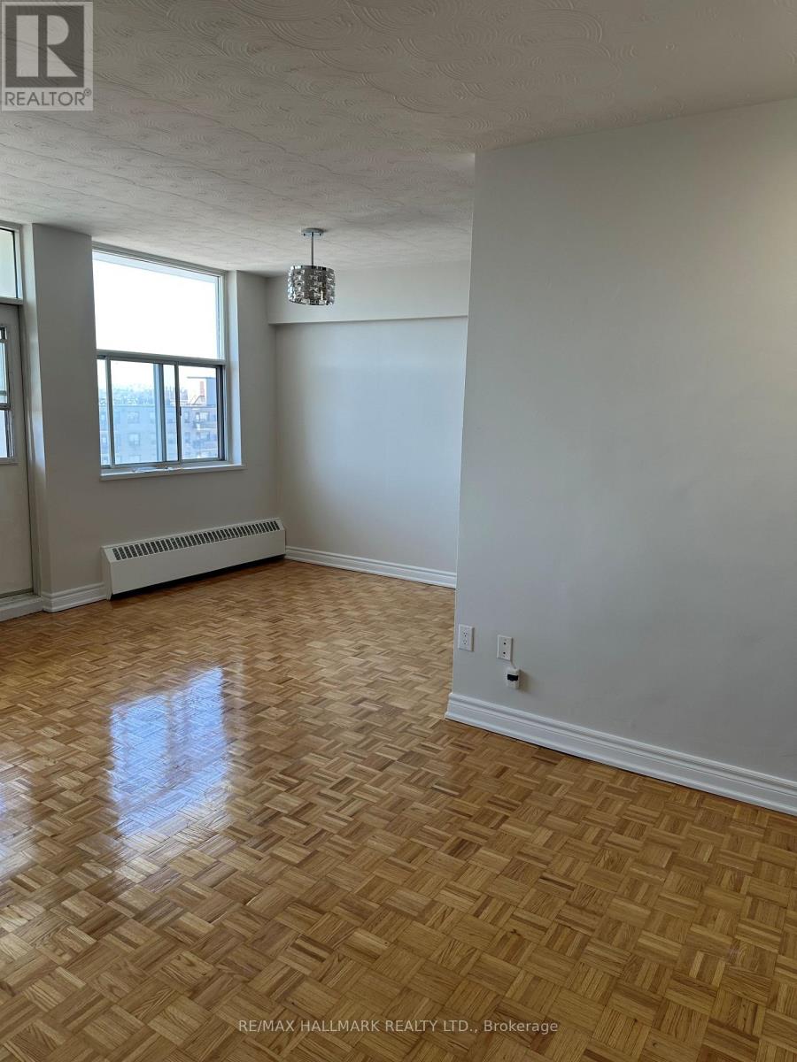 A room with a wooden floor and a window with a radiator beneath it.