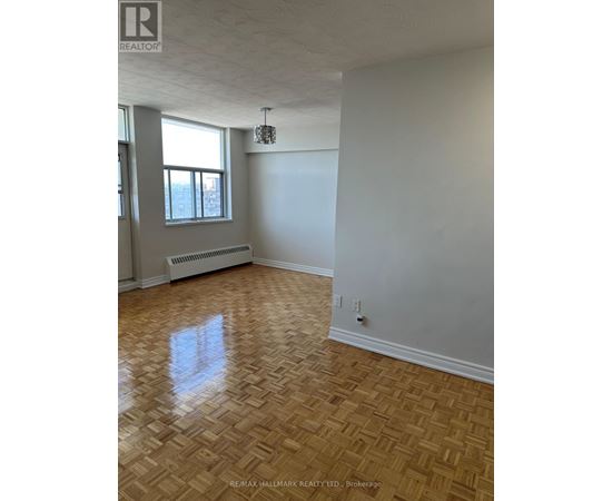 A room with a wooden floor and a window with a radiator beneath it.