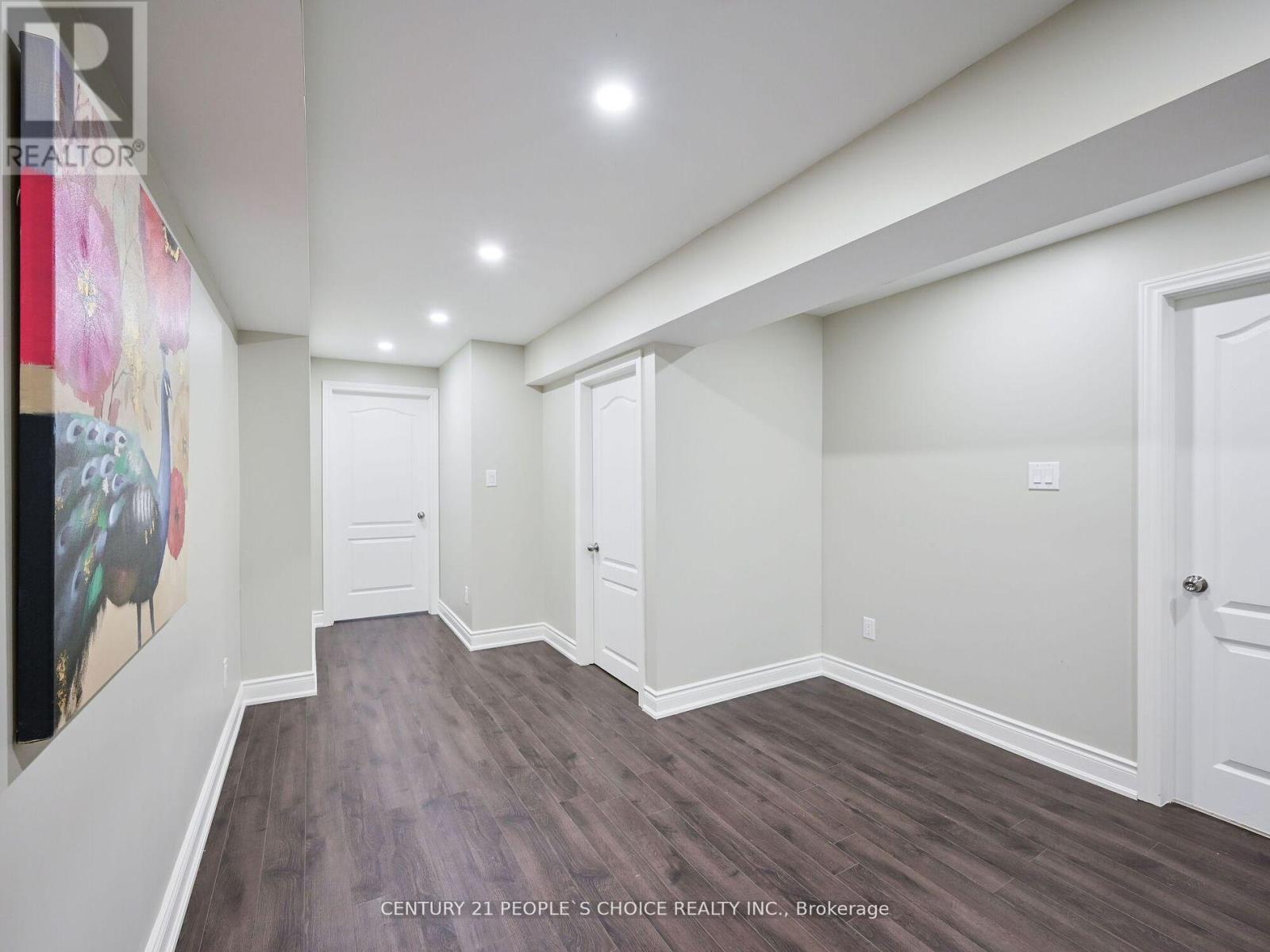 A spacious room with wood flooring and white walls.