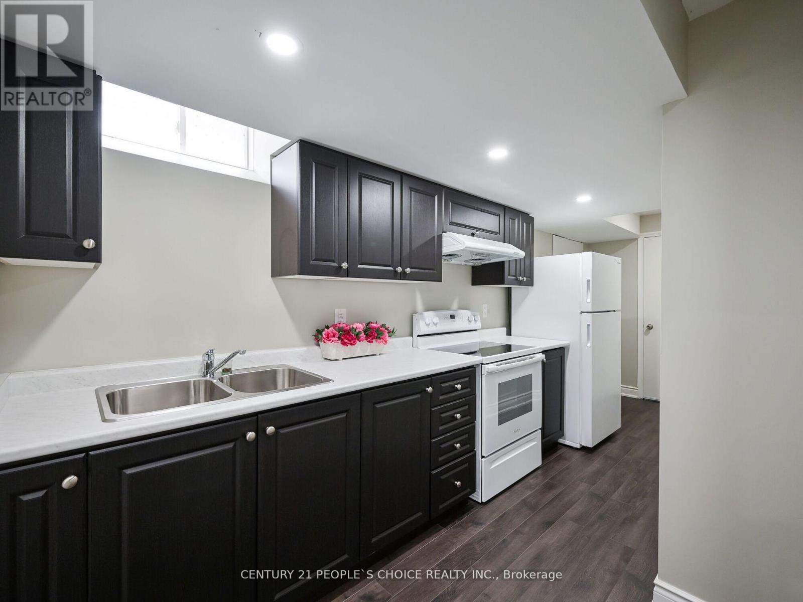 A kitchen with black cabinets and a white refrigerator.