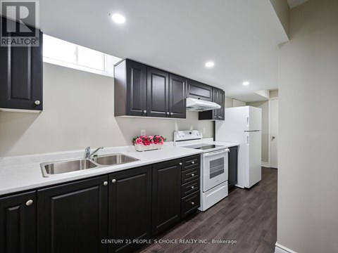 A kitchen with black cabinets and a white refrigerator.