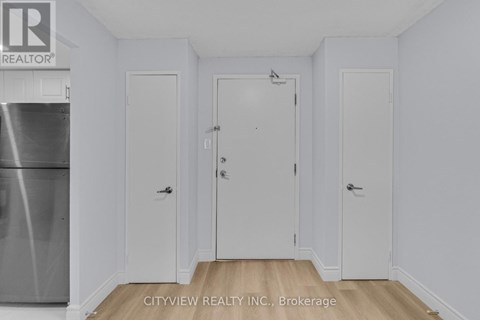 A white refrigerator is in the corner of a small kitchen.