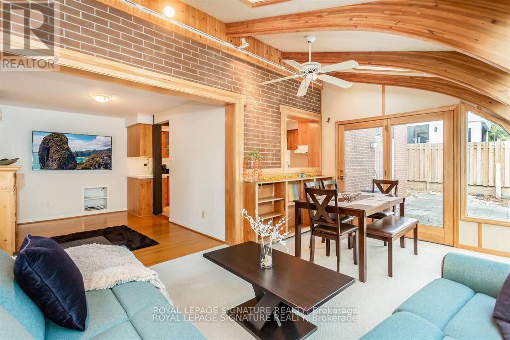 A living room with a couch, a dining table, and a ceiling fan.