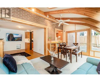 A living room with a couch, a dining table, and a ceiling fan.