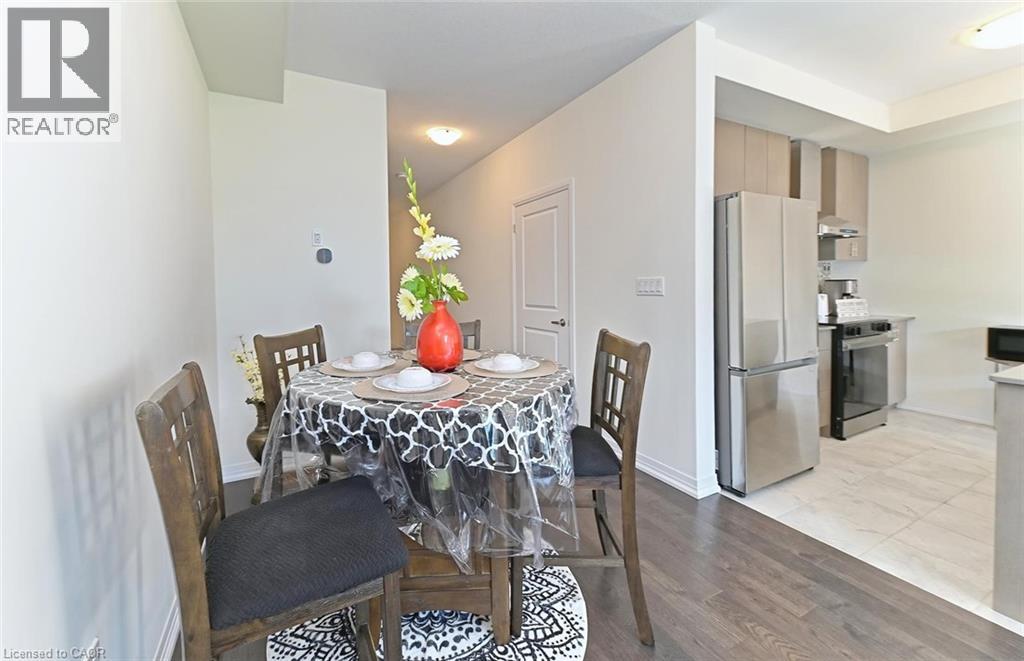 A dining room with a table set for two and a refrigerator in the corner.