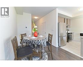 A dining room with a table set for two and a refrigerator in the corner.