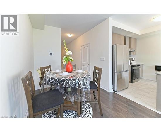 A dining room with a table set for two and a refrigerator in the corner.