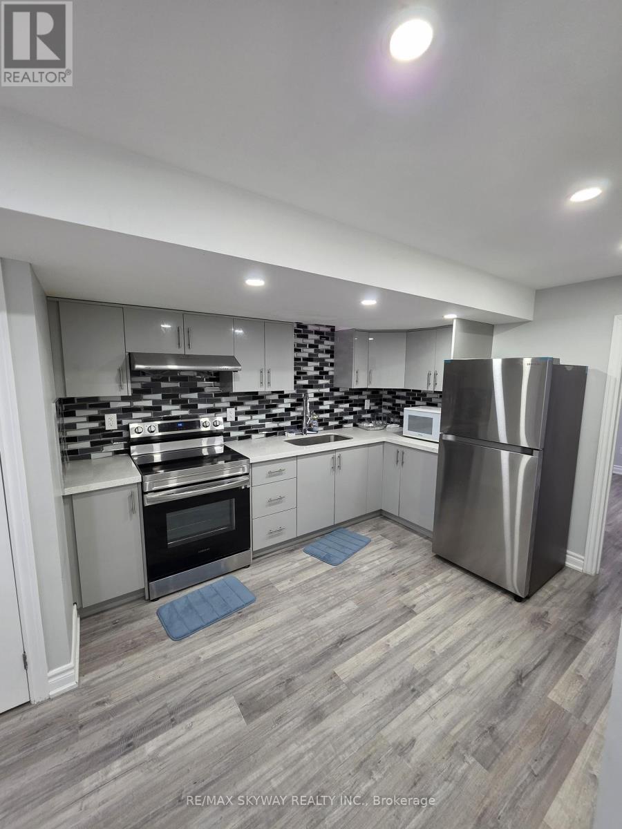 A modern kitchen with a stainless steel refrigerator and wooden flooring.
