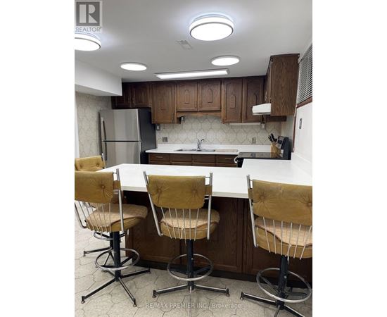 A kitchen with a white counter top and brown chairs.