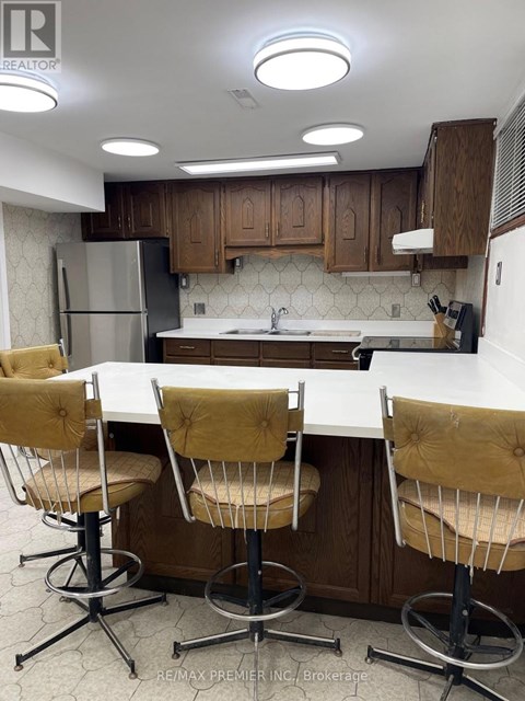 A kitchen with a white counter top and brown chairs.
