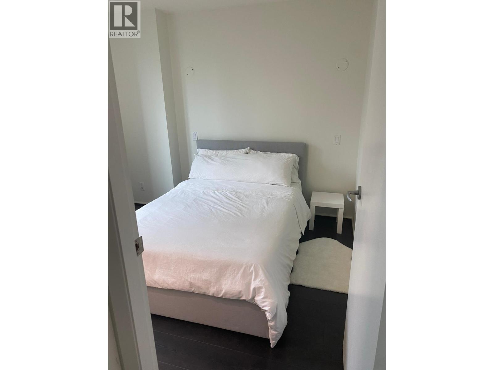 A bedroom with a bed, nightstand, and chair.
