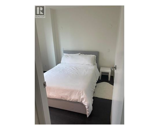 A bedroom with a bed, nightstand, and chair.