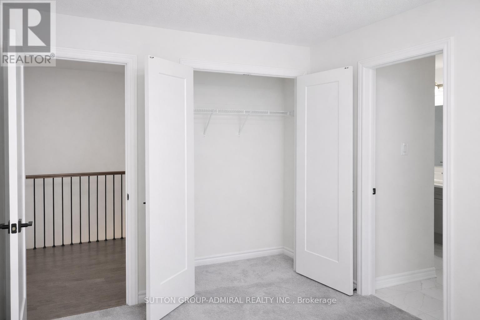 A realtor photo of a white bedroom with a doorway leading to another room.