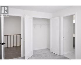 A realtor photo of a white bedroom with a doorway leading to another room.