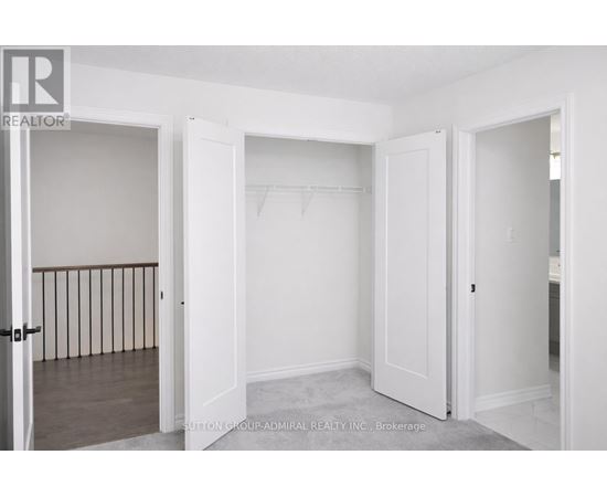 A realtor photo of a white bedroom with a doorway leading to another room.