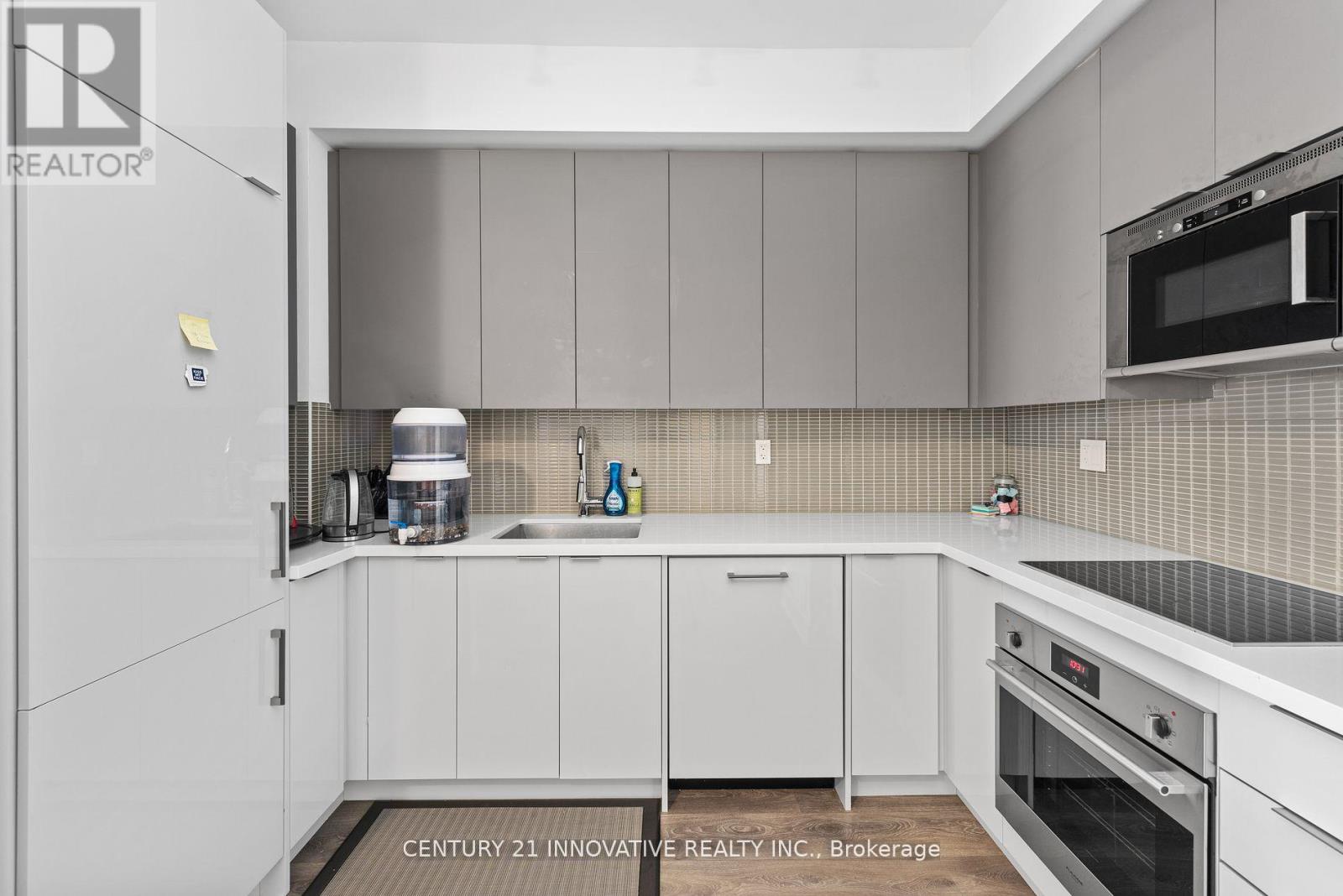 A modern kitchen with white cabinets and a tiled backsplash.
