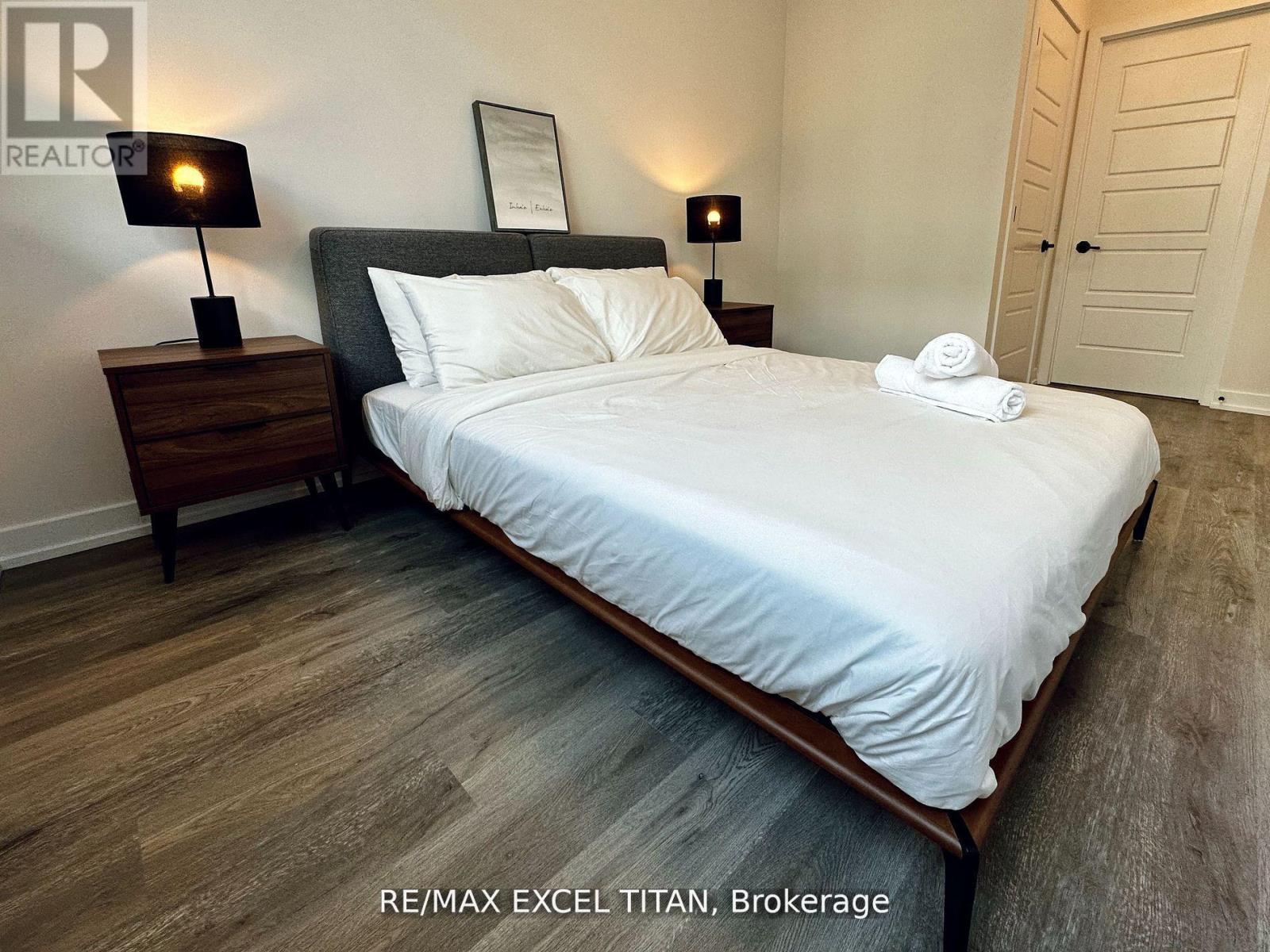 A bedroom with a large bed and two lamps on either side of the bed.