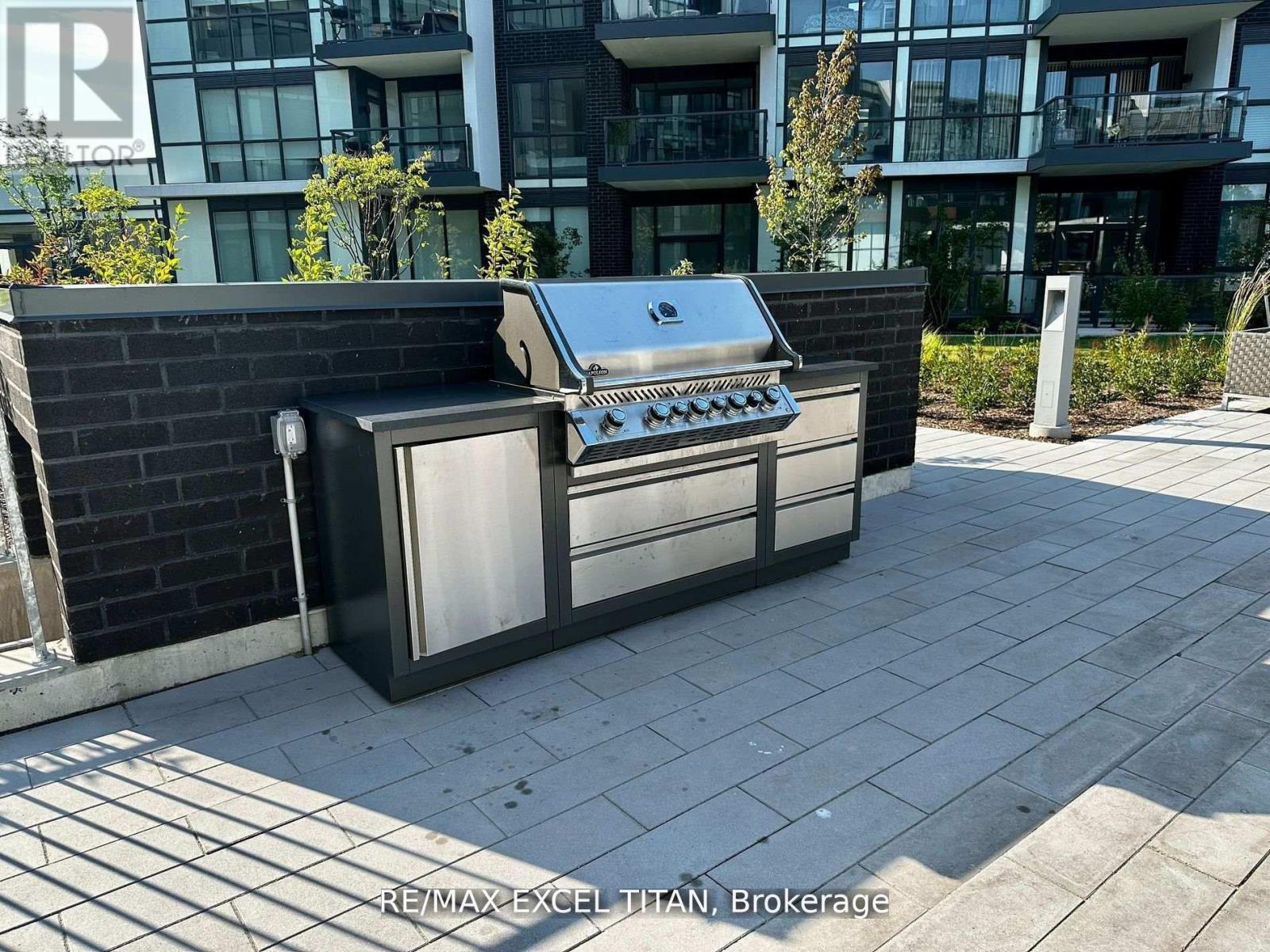 A BBQ grill is placed on a paved area in front of a building.