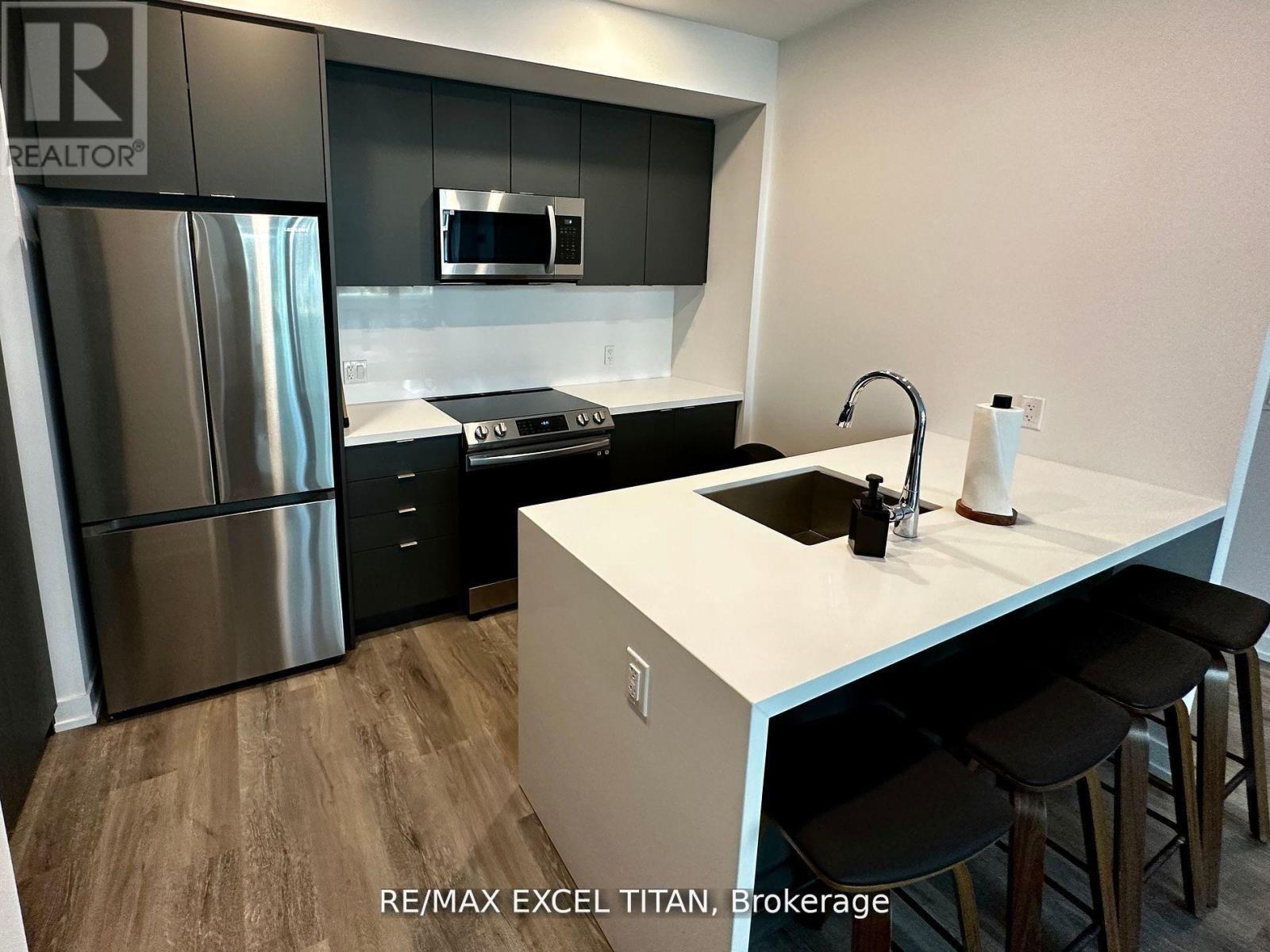 A modern kitchen with a refrigerator, microwave, oven, and sink.