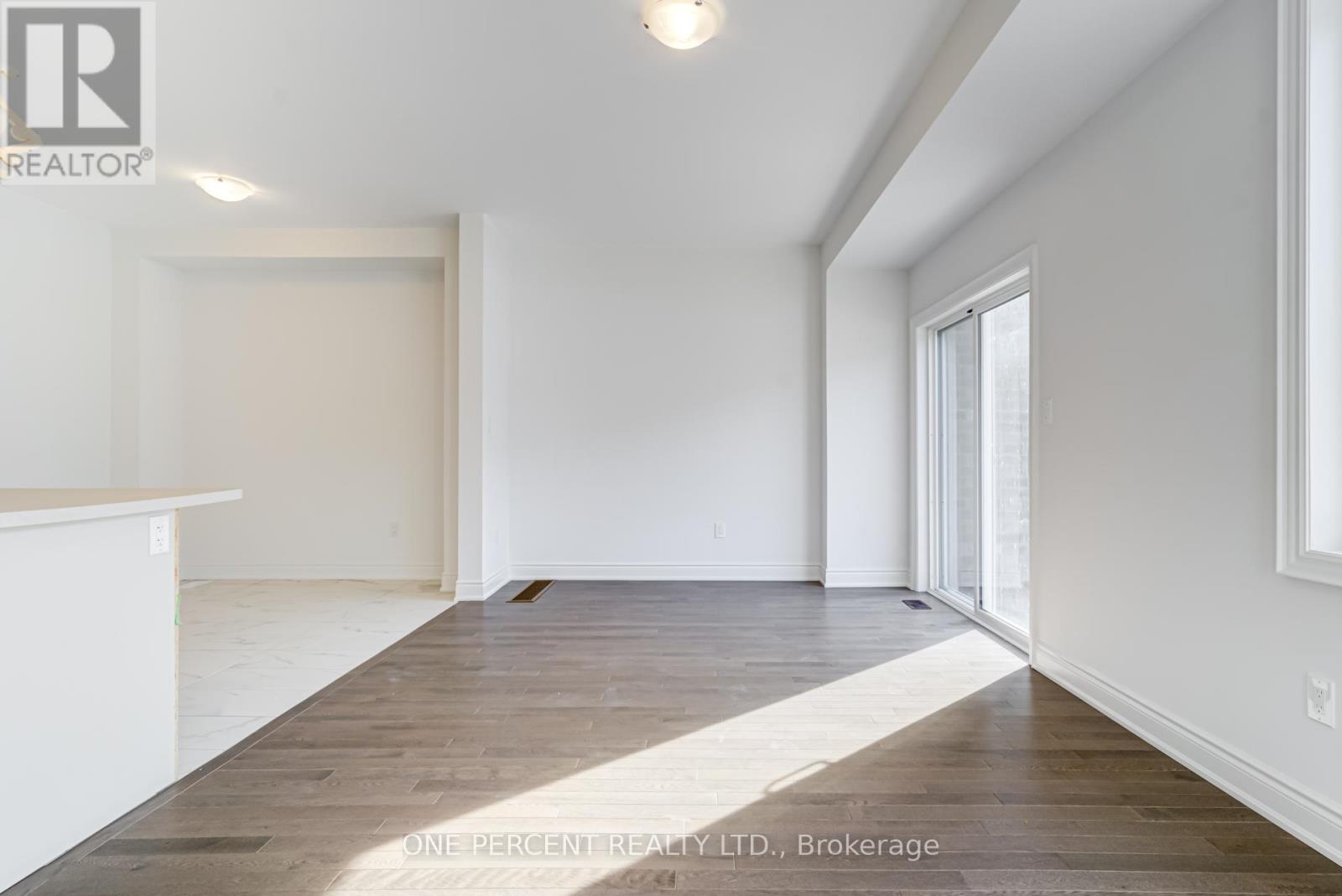 A spacious room with wooden flooring and white walls.