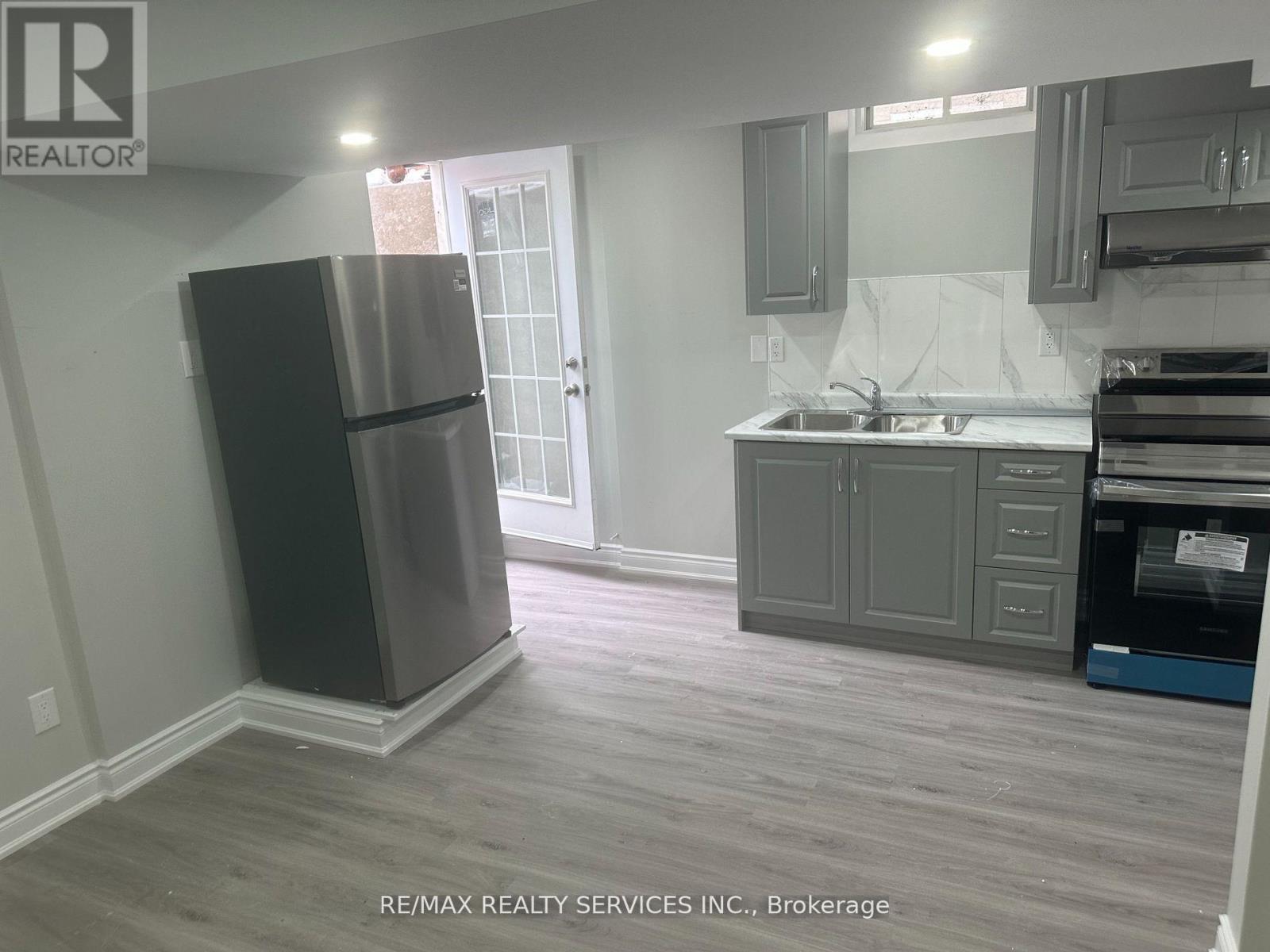 A kitchen with a refrigerator, sink, and cabinets.