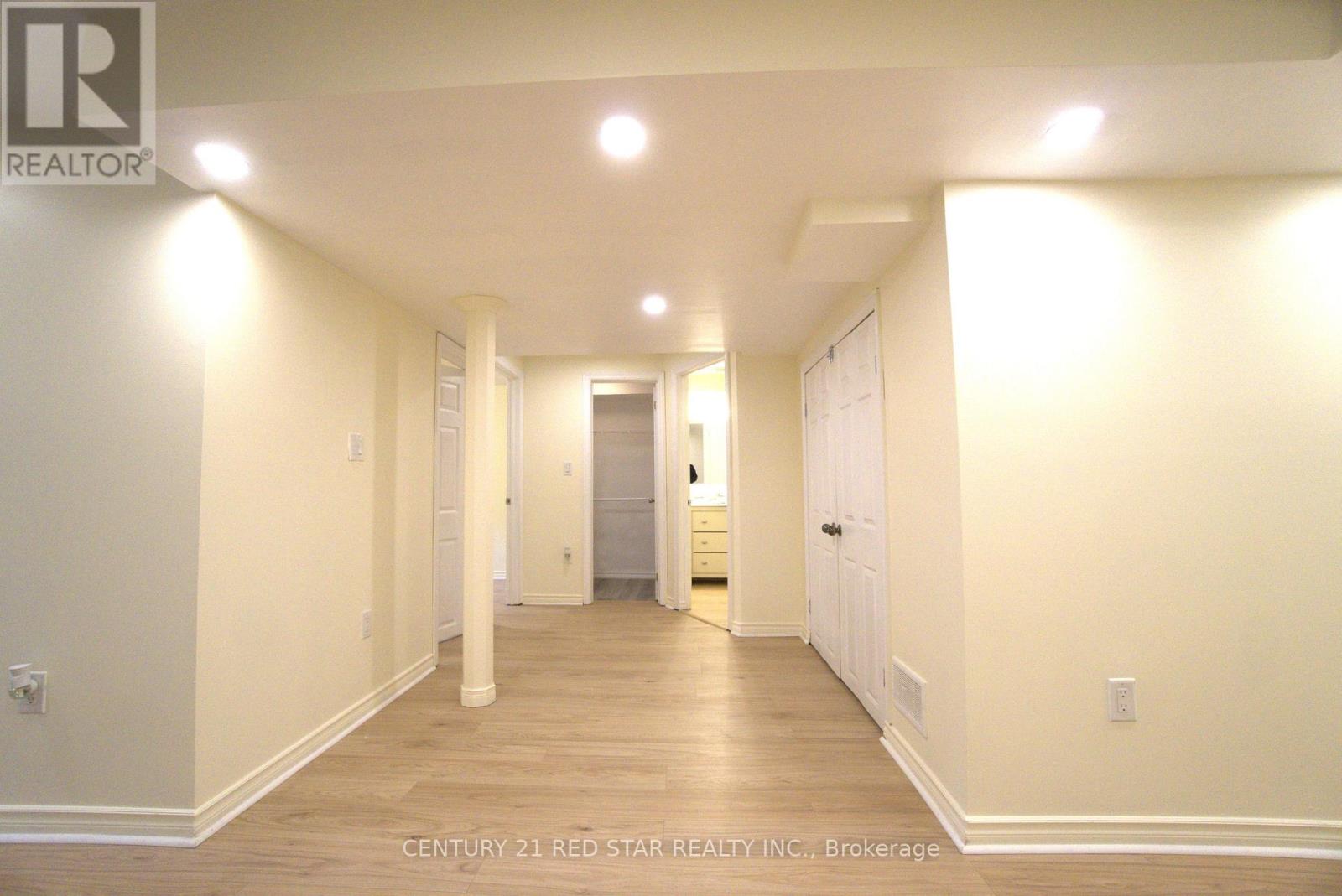A hallway with white walls and wood flooring.