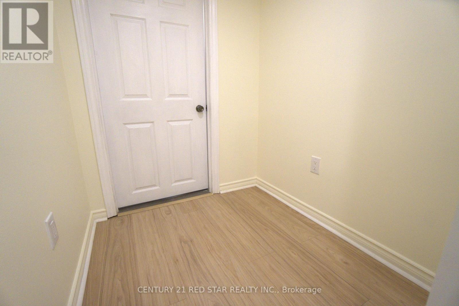 A white door is in a room with wooden floors and white walls.