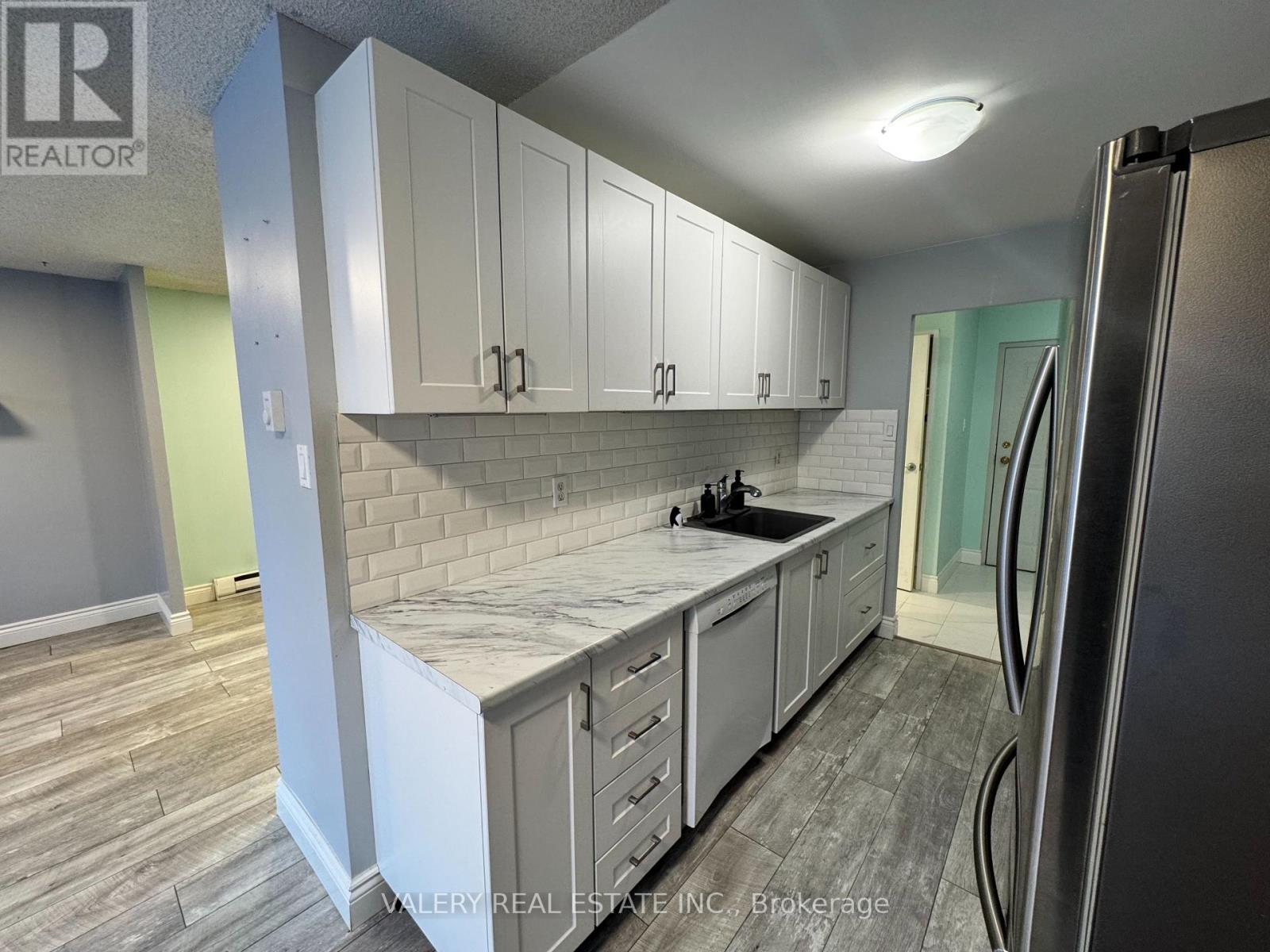 A kitchen with white cabinets and a marble countertop.