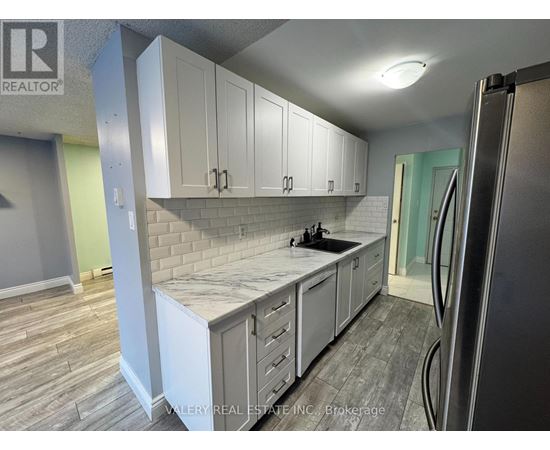 A kitchen with white cabinets and a marble countertop.