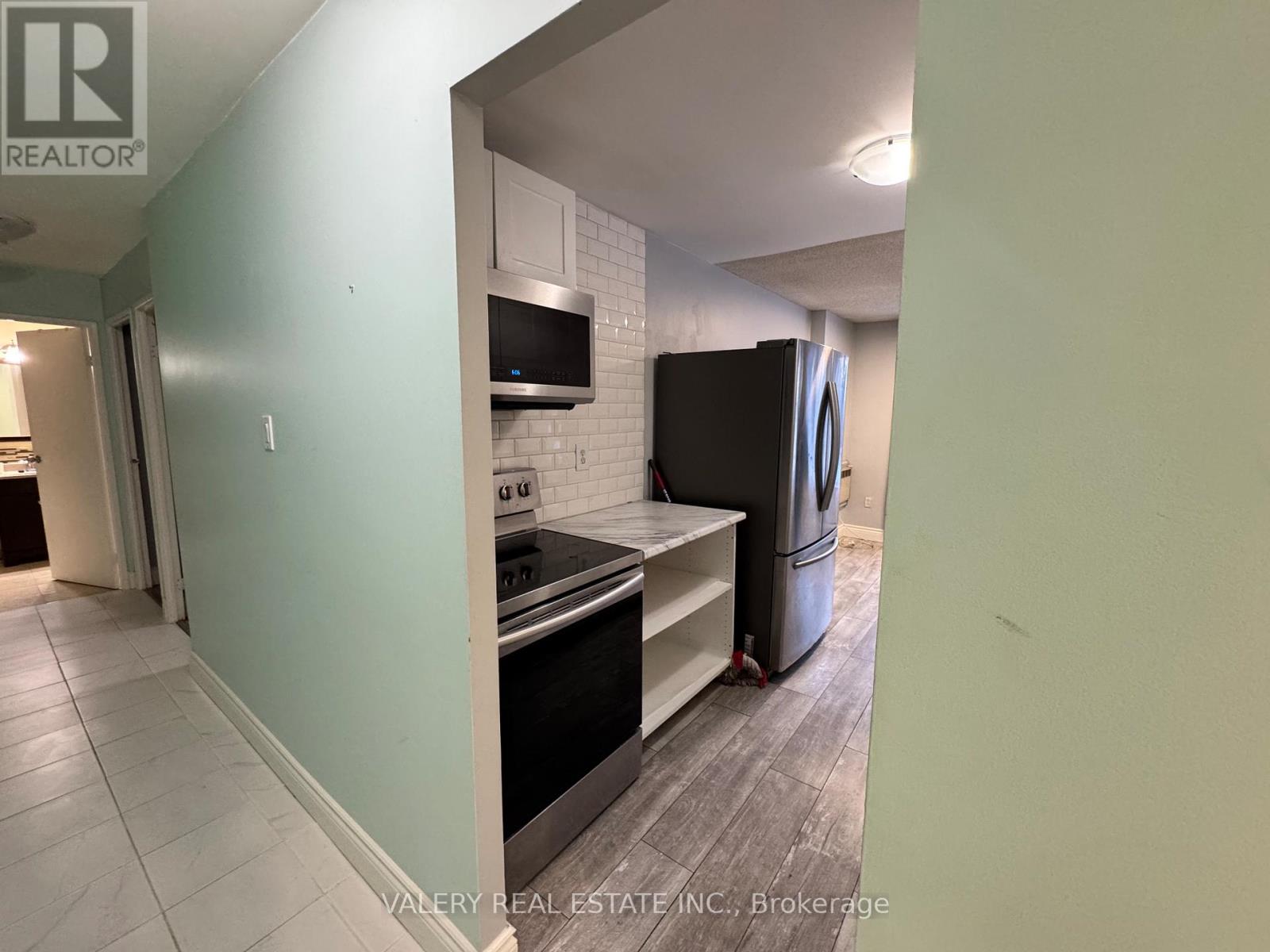A kitchen with a stove top oven and a refrigerator.