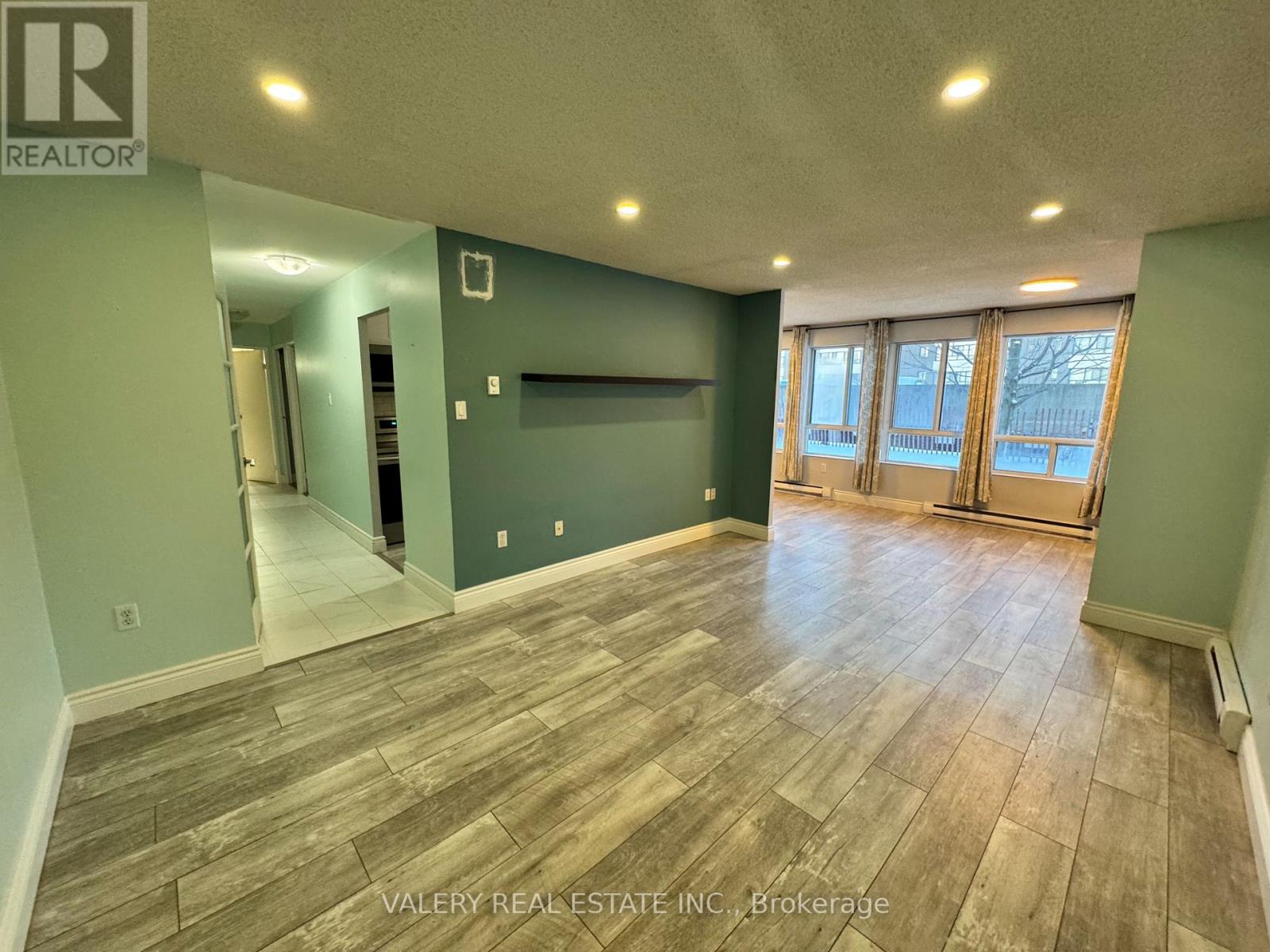 A room with wood flooring and a wall with a window.
