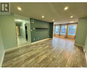 A room with wood flooring and a wall with a window.