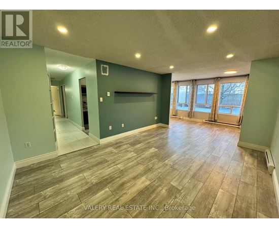 A room with wood flooring and a wall with a window.