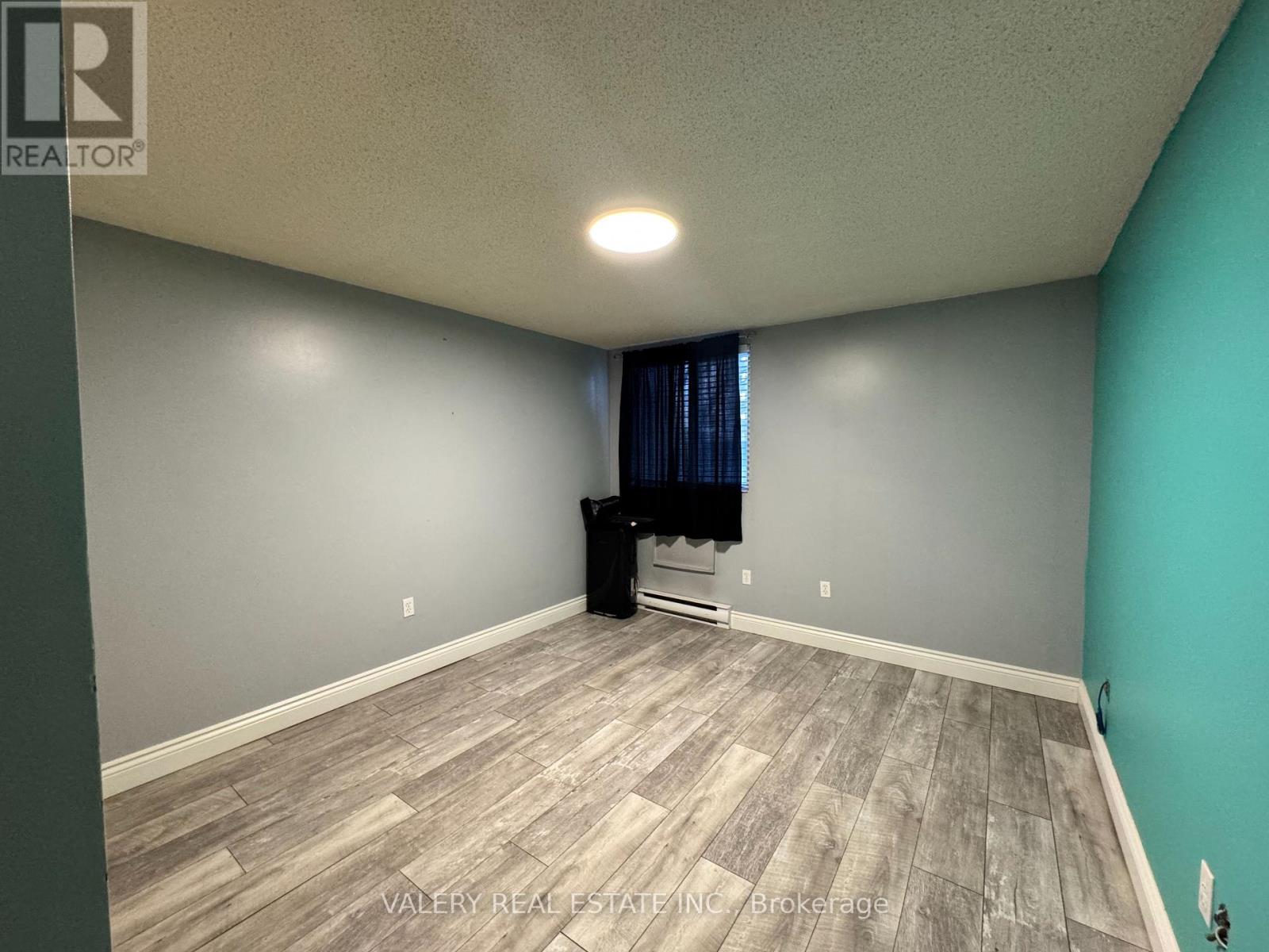 A room with a grey wall and a wooden floor.
